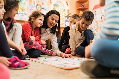 Happy early years teacher educating a large group of children