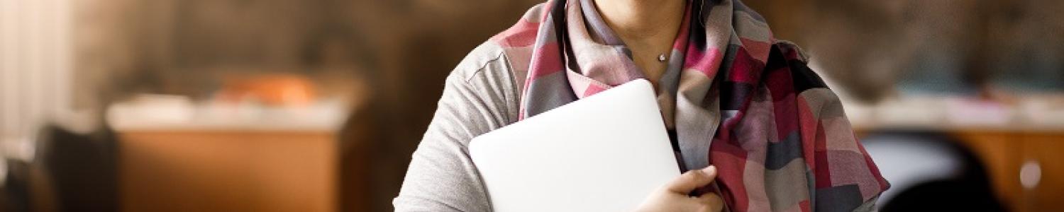 Educator smiling and holding a laptop