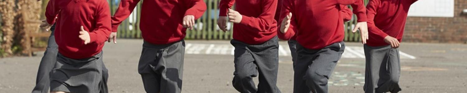 A group of children in school uniform running towards the camera