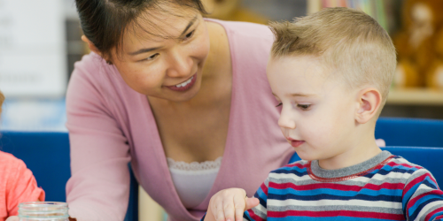 educator and child sitting at table