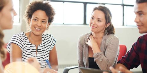 Educators with pleased expressions talking together at a table