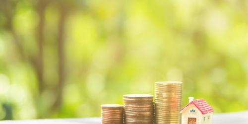 A stack of coins next to a toy wooden house