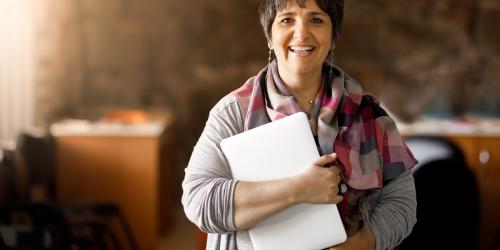 Educator smiling and holding a laptop