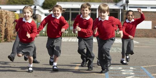 A group of children in school uniform running towards the camera