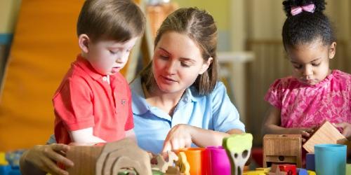 Educator and children sitting at a table and learning about blocks