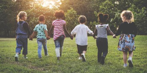 Children holding hands together walking in the park