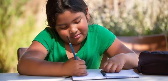 School aged child writing in a notebook