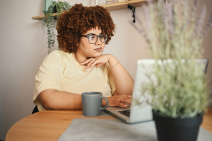 Educator working at a desk with a hot drink and a laptop